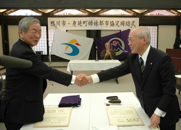 Kamogawa Mayor Honda (left) and Minobu Mayor Yoda shake hands after signing a sister city agreement (Photo by Mainichi Newspaper/AFLO) [2400].