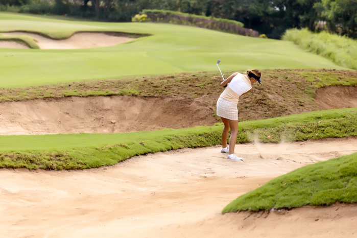 Female golf player in sand trap, Bali, Indonesia Woman playing golf in sand trap, Dreamland, Bali, Indonesia