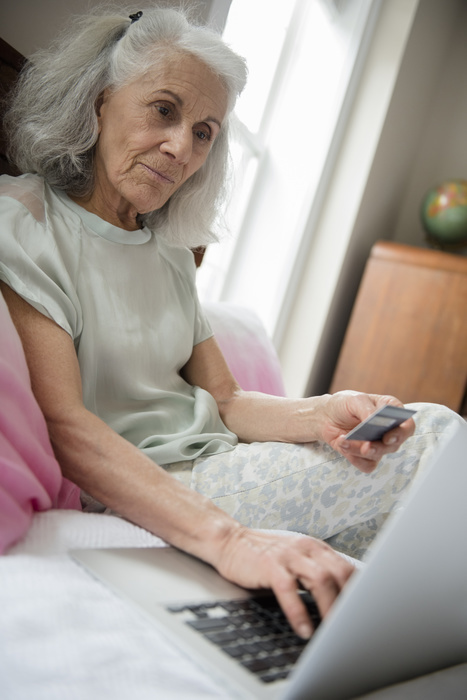 Older woman shopping online with credit card and laptop