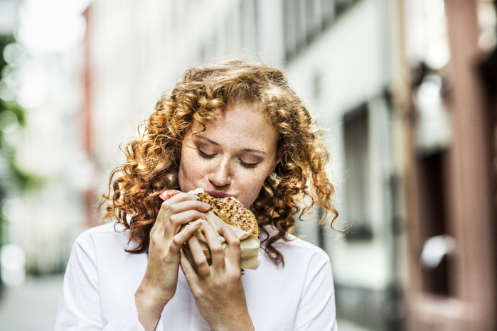 female Portrait of young woman eating bagel outdoors