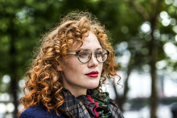 Portrait of redheaded young woman with red lips wearing glasses