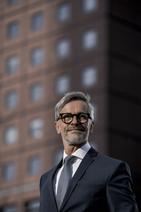 Grey-haired businessman in front of red skyscraper