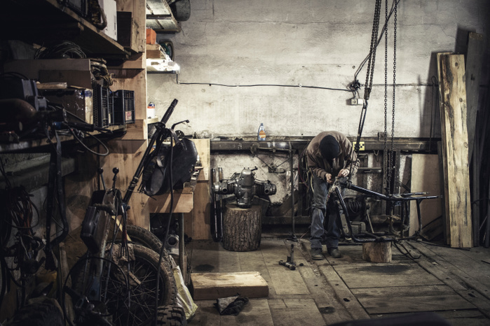 Mechanic repairing dismantled vintage motorcycle in workshop