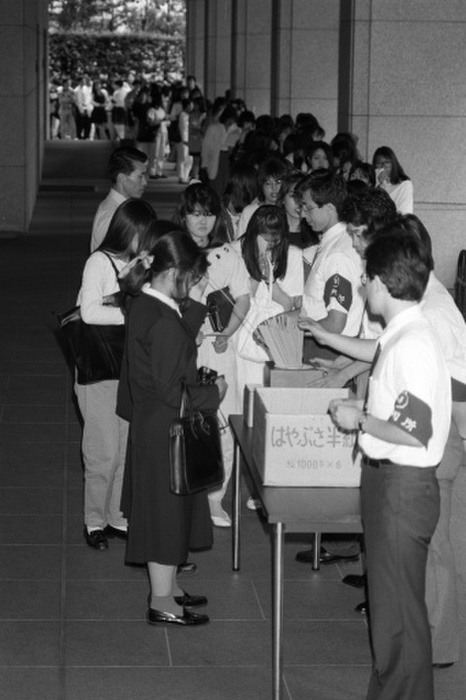 Fans line up for tickets to hear Imai s first trial. On the afternoon of May 5, the 9th Criminal Division of the Tokyo District Court held the first trial in the case of Hisashi Imai, 23, a guitarist in the popular young rock band BUCK TICK, who was accused of violating the Narcotics Control Law by receiving the hallucinogenic drug LSD from a friend. At his arraignment, Imai fully admitted the facts of the indictment and stated in a question to the defendant,  I deeply regret this and will never cause such an incident again. The prosecution concluded the hearing by stating that the defendant  has led an extremely licentious life and must be severely punished,  and requested a sentence of six months in prison. At the Tokyo District Court, June 5, 1989.