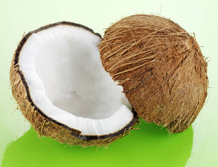 TWO COCONUT HALVES WITH HUSK ON GREEN