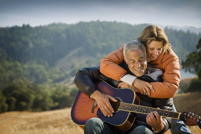 senior couple Woman hugging man playing guitar