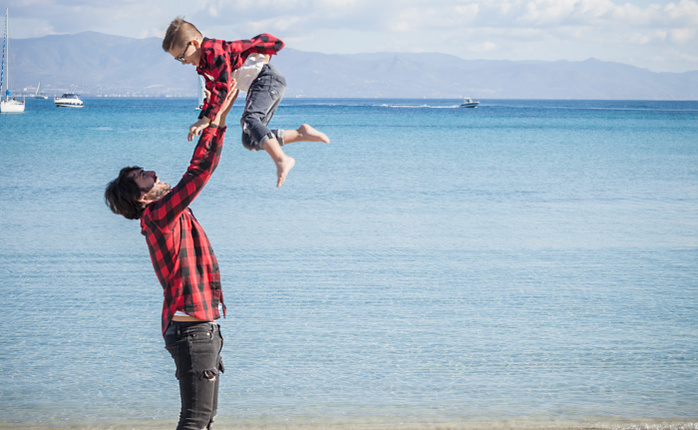 Father and son on beach, father lifting son in air