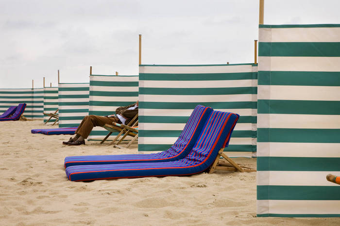 Man sitting on a beach chair between wind screens, North Sea, Belgium