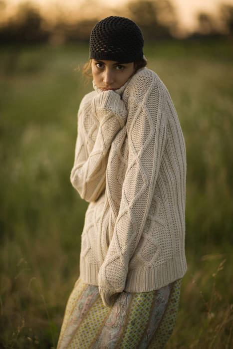 Woman standing outdoors wearing thick sweater, looking at camera, portrait
