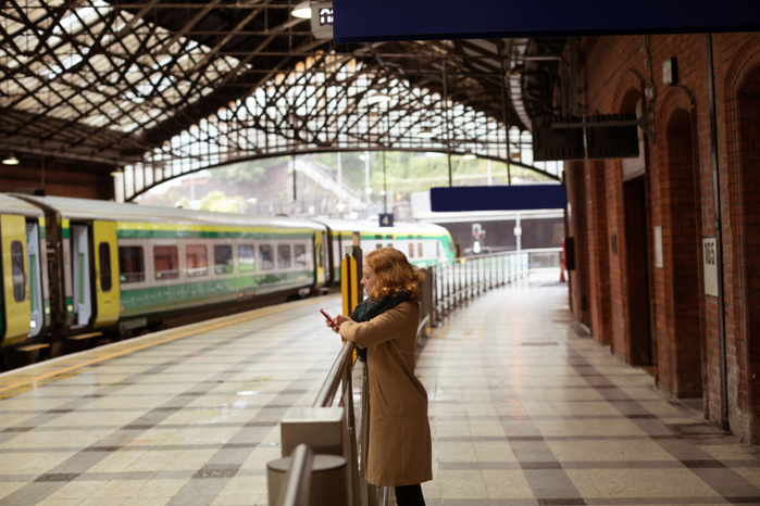 Beautiful young woman standing on railway platform using her mobile phone Beautiful young woman standing on railway platform using her mobile phone