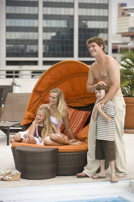 Portrait of happy family lounging poolside on rooftop terrace in the city