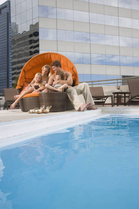 Portrait of family lounging poolside on rooftop terrace in the city