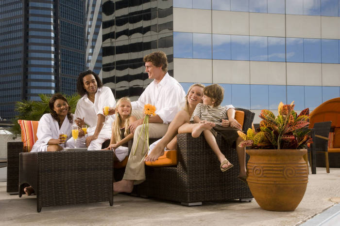 Portrait of family and friends lounging poolside on rooftop terrace in the city