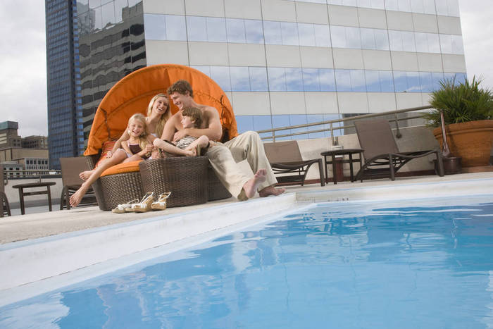 Portrait of family lounging poolside on rooftop terrace in the city