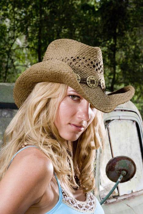 Portrait of young blonde cowgirl in cowboy hat beside truck outdoors