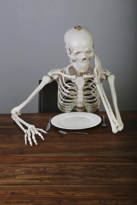 Skeleton with supported head sitting at table, Germany, Europe