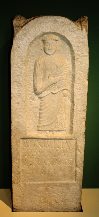 Limestone tombstone for Maximilla Bassi. Tunisia, Punic, 2nd-3rd century AD from Carthage. This finely carved monument was set up in memory of a woman called  maximilla Bassi. The Latin inscription says 'Maximilla Bassi, pious daughter, lived neneteen years. Here she is placed.' After the Roman annexation of Carthage in 146BC it became more fashionable to use Latin for inscriptions although Phoenician remained the everyday language used. The shallow niche is carved with an image of a female figure wearing a pleated tunic and mantle, presumably Maximilla.