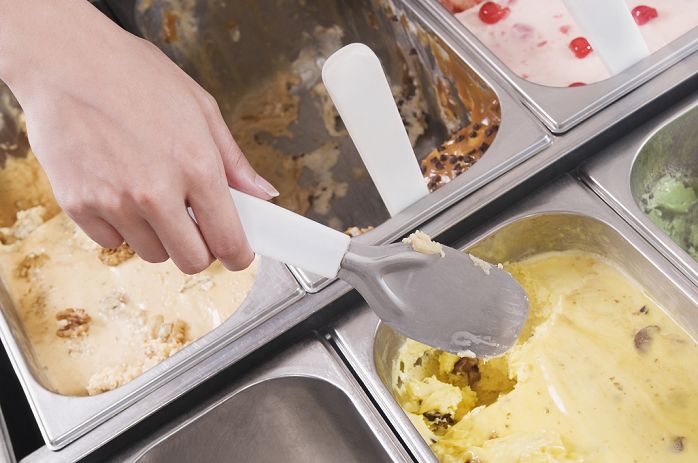 Man's hand taking scoop of ice cream out of container
