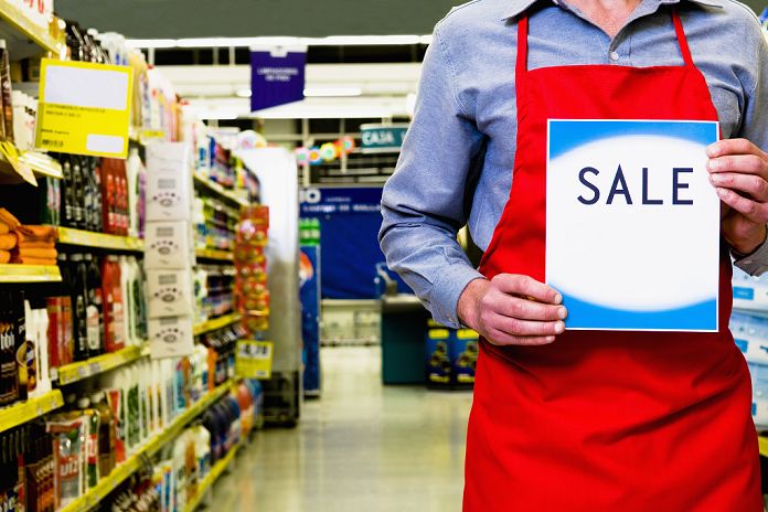 Supermarket staff announcing a sale Sales clerk holding a sale signboard