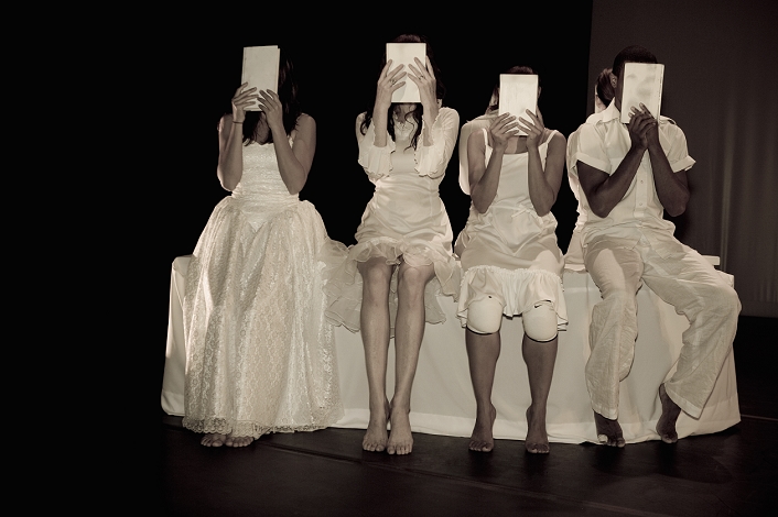Four people hiding their faces with papers