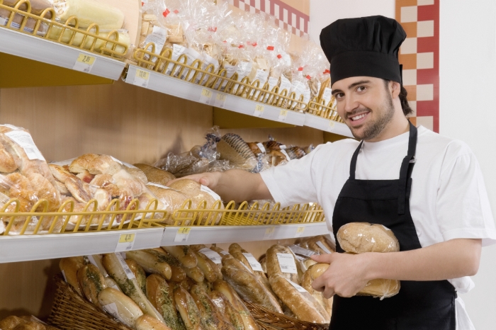 Sales clerk holding breads in a supermarket