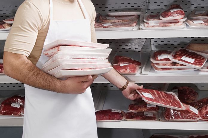 Sales clerk holding a stack of meat in a supermarket