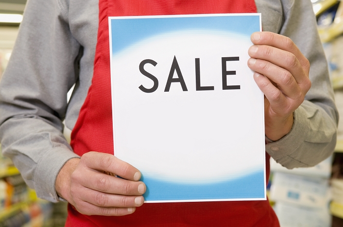 Mid section view of a salesman holding a Sale sign