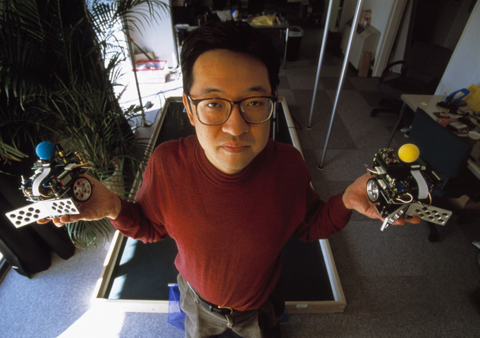 Dr Hiroaki Kitano Dr Hiroaki Kitano, Japanese artificial intelligence researcher, holding two members of his miniature robot football team. Kitano organised the first RoboCup  World Cup Robot Soccer  competition in 1997. The competition promotes the development of intelligent robots for use in hostile environments, and drives general advances in robot design and behaviour. The matches consist of two five minute periods of play between two teams of up to five robots, with categories for robots of different sizes. Kitano is the founder and senior researcher at the Sony Computer Science Laboratory, Japan. Photographed in Japan.