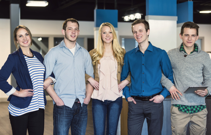 Portrait of a group of young millennial professionals standing together arm in arm in the workplace; Sherwood Park, Alberta, Canada
