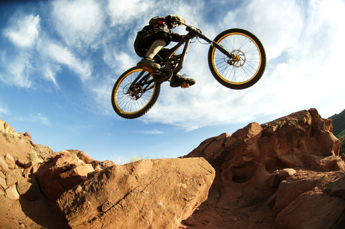 cycling Mountain biker performing stunt in mid air against sky