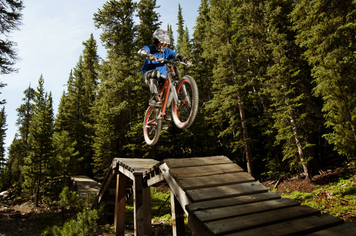 mountain bike Low angle view of man performing stunt on sports ramp in forest