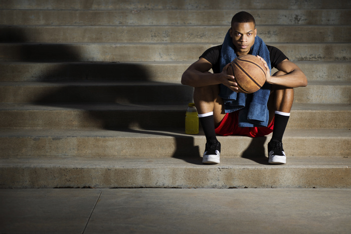 Young Man Sitting on Steps Holding Basketball  Portrait of athlete with basketball sitting on steps