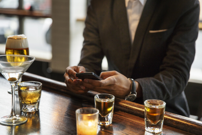 Midsection of man using smart phone while sitting in bar