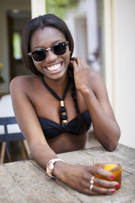 female Portrait of happy woman in black bikini top holding drink at outdoor table