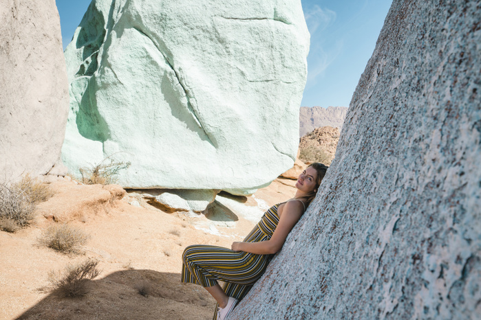 Portrait of woman leaning on rock at desert