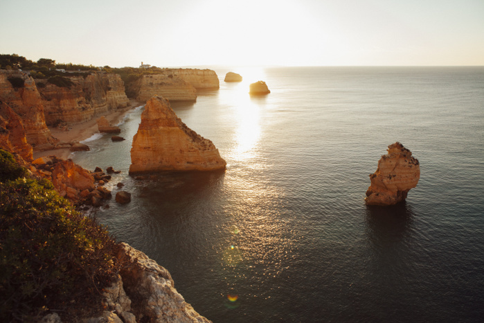 Portugal Scenic view of mountains by sea against sky at Praia da Marinha during sunset