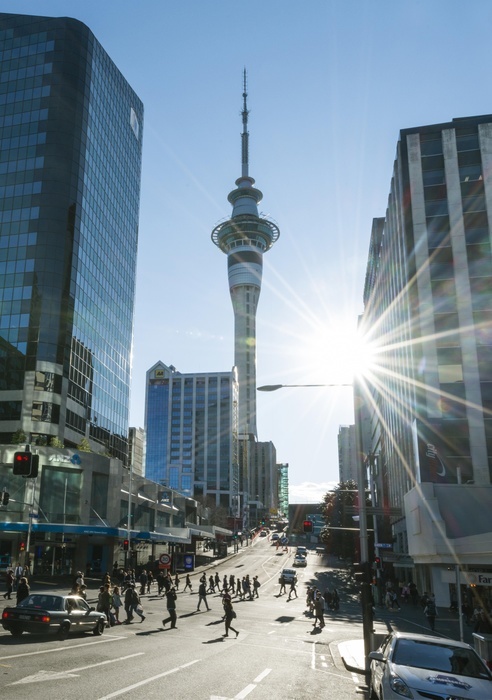 New Zealand Pedestrians crossing street, Sky Tower, backlit with sun star, Central Business District, Auckland Region, North Island, New Zealand, Oceania, Photo by Moritz Wolf