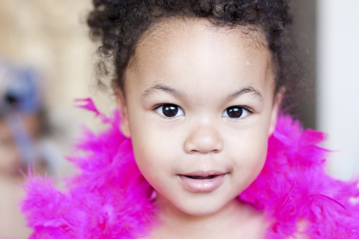 Portrait of cute girl with pink feather boa at home