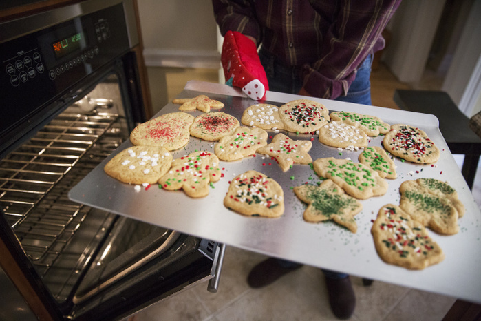 Senior Male Senior man holding gingerbread cookies in baking sheet at home