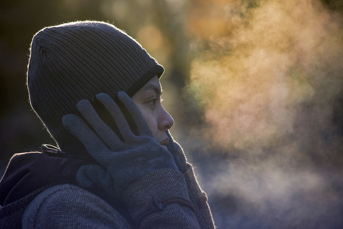 Close-up of woman exhaling breath vapor at park during winter