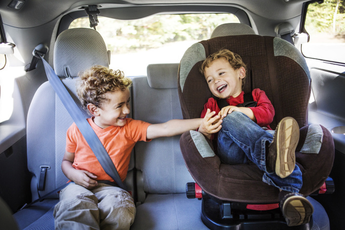 Boy tickling brother while sitting in car