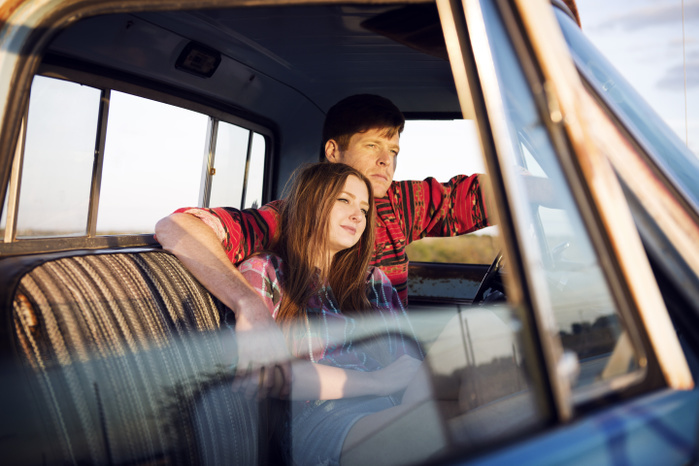 Couple sitting in pick-up truck during sunset