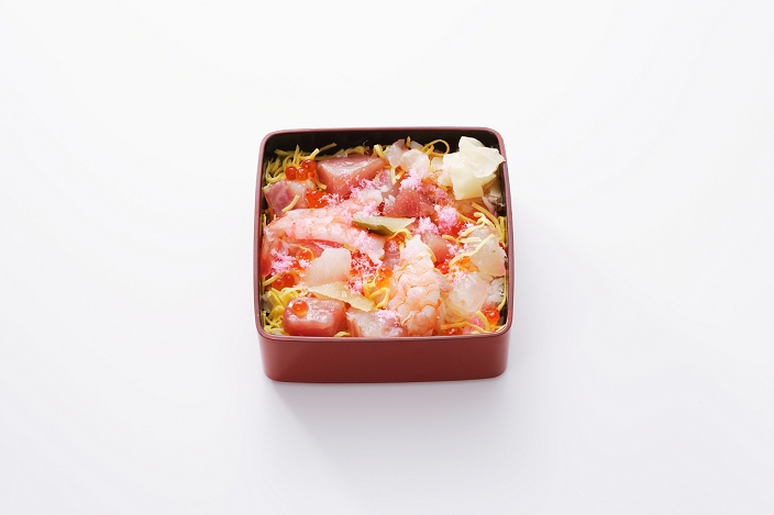 sushi rice in a box or bowl with a variety of ingredients sprinkled on top