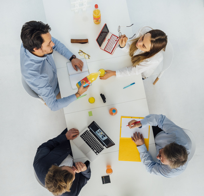 Four business people at meeting table in office, top view Four business people at meeting table in office, top view