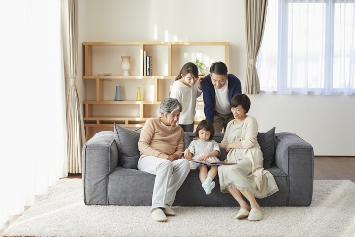 Three generations of a Japanese family relaxing on a sofa