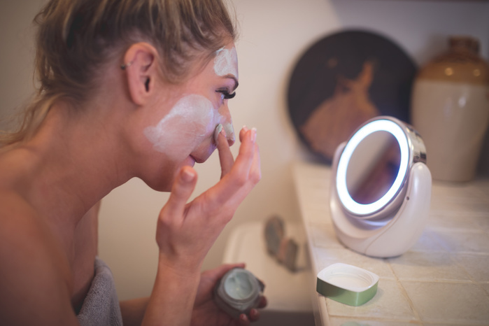Woman applying facial cream in bathroom at home Woman applying facial cream in bathroom at home