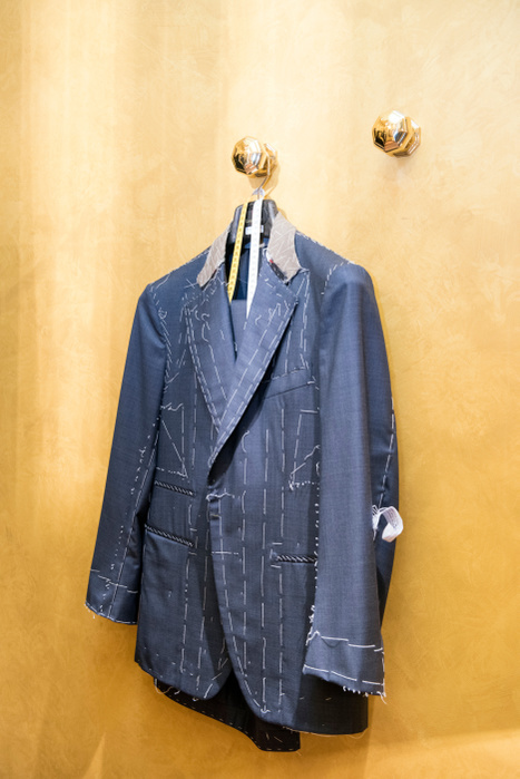 Unfinished bespoke jacket hanging in tailors shop