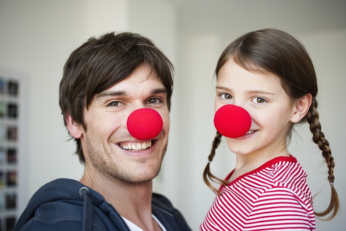Father and girl wearing red noses