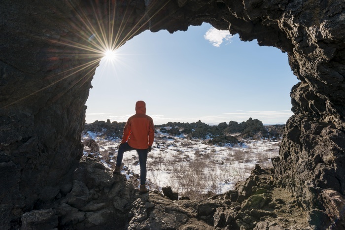 Iceland Man in a rock arch with sunbeams, volcanic landscape, volcanic area Krafla, Dimmuborgir National Park, M vatn, Iceland, Europe, Photo by Moritz Wolf