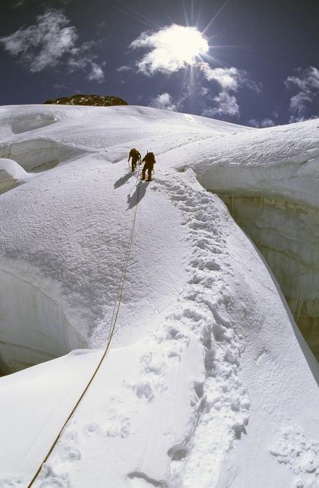 Switzerland Two mountaineers crossing a big crevasse during an ascent of Mount Piz Glueschaint, Bernina Range, Graubuenden Canton, Switzerland, Europe, Photo by Michael Fischer